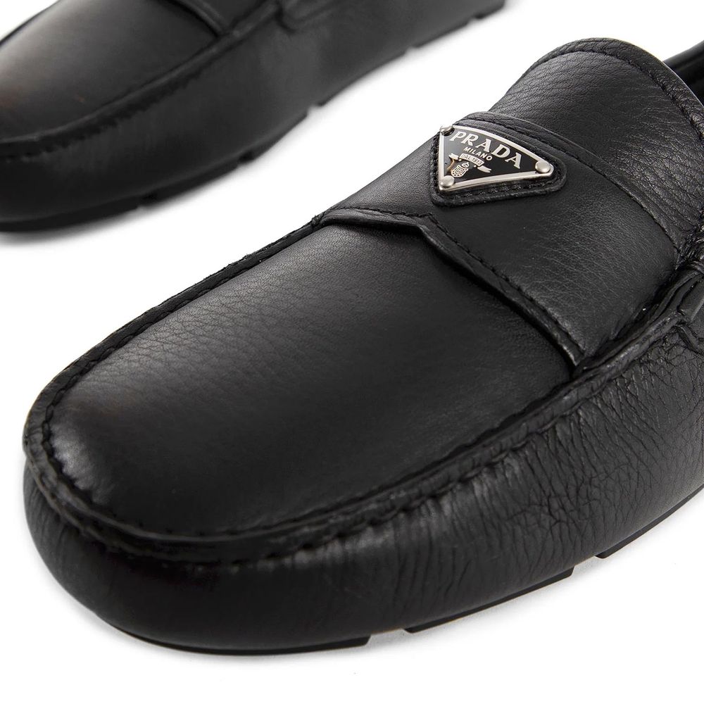 Black leather moccasin shoe with Prada logo on a white background